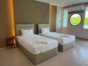 deux lits dans une chambre avec fenêtre dans l'établissement Madee House - มาดีเฮ้าส์,  12 autres photos