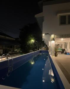 a swimming pool at night in front of a house at Easy Monday Capsule Hotel Bangkok in Bangkok