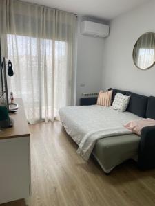 a bedroom with a bed and a couch and a window at Acogedor apartamento Vallparadís con parking in Terrassa
