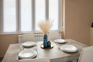 un tavolo da pranzo con piatti bianchi e un vaso con l'erba di That's Amore Cernobbio - Lake Como Apartment a Cernobbio