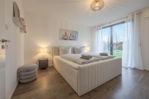 a white bedroom with a large bed and a window at Konny in Gaienhofen