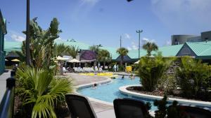 uma piscina de resort com cadeiras e pessoas na água em Beachside Hotel & Suites Cocoa Beach - Port Canaveral em Cocoa Beach