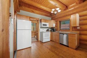 a kitchen with white appliances and wooden walls at Rustic Chalet Perfect Getaway for Groups in Golden