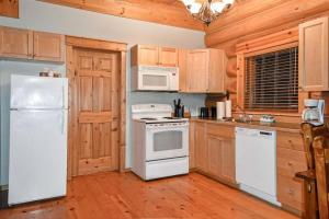 a kitchen with white appliances and wooden cabinets at Authentic, Timber Log Cabin Perfect for Groups in Golden