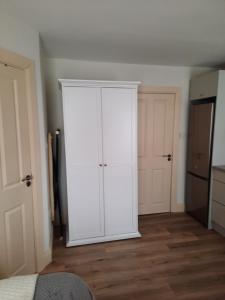 een witte kast in een kamer met een slaapkamer bij Studio with kitchen and bathroom in Cork