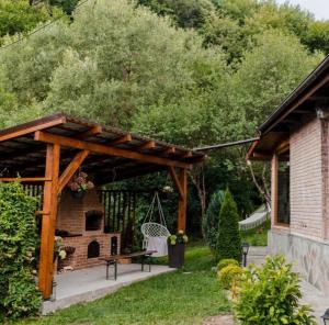 a wooden pavilion with a picnic table and a brick oven at Cabana Ana in Feleacu