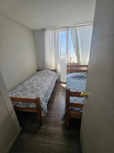 a small bedroom with a bed and a window at Departamento entero doble iquique in Iquique