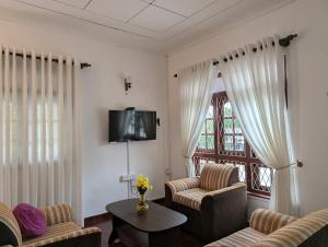 a living room with chairs and a tv and a window at Condo NÖJE in Weligama