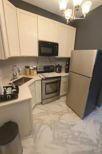 una cucina con mobili bianchi e un frigorifero in acciaio inossidabile di Fully Equipped 3 Beds Apartment, 5 min from the Arch a Saint Louis