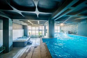 a large swimming pool with a tub in a room at Complex Turistic Central in Băile Herculane
