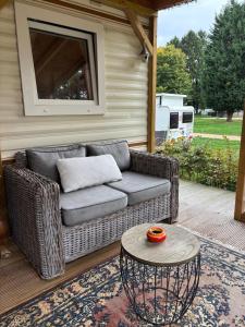 eine Korbcouch auf einer Terrasse mit einem Tisch in der Unterkunft Het Heideverblijf in Heerlen
