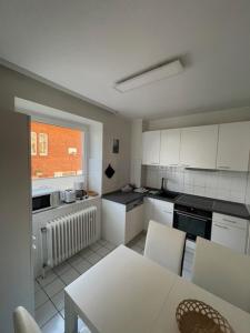 a kitchen with a table and white cabinets and a window at Seepferdchen in Timmendorfer Strand