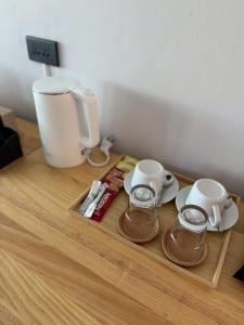 - un plateau avec deux tasses et une cafetière sur une table dans l'établissement Madee House - มาดีเฮ้าส์, 