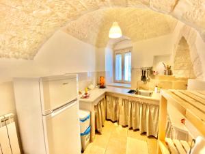 a kitchen with a white refrigerator and a sink at Trulli Phoenix Alberobello in Alberobello