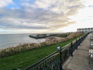 a bird sitting on a fence next to the water at Eleven Tides in Seaham