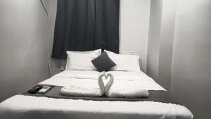 a bed with white sheets and two towels on it at THE NEXOS UNIQUE SUITEs in Jāmb