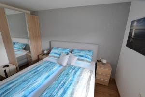 een slaapkamer met een bed met blauwe lakens en kussens bij Wohnen bei Gerlis - DZ 106 in Burbach