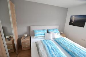 een bed met blauwe en witte lakens en kussens bij Wohnen bei Gerlis - DZ 106 in Burbach
