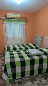 een slaapkamer met een bed met een geruite deken bij Diana hotel 1 in Capitán Miranda