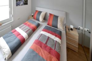 een slaapkamer met twee bedden met kleurrijke kussens erop bij Wohnen bei Gerlis - DZ 105 in Burbach