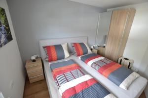 een slaapkamer met 2 bedden en kleurrijke gestreepte kussens bij Wohnen bei Gerlis - DZ 105 in Burbach