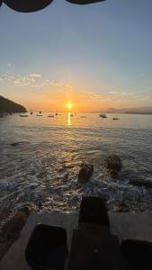 un coucher de soleil sur une étendue d'eau avec des bateaux dans l'établissement Casa da Barra, à Ubatuba
