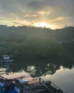 un groupe de bateaux sur une rivière avec le soleil couchant dans l'établissement Casa da Barra, à Ubatuba