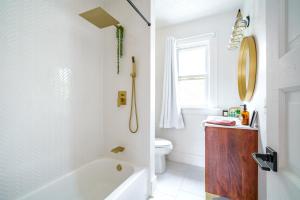 a white bathroom with a tub and a toilet at Jungle House Luxury Homes - Columbus Downtown Short North - Steps to Convention Center & Nationwide Arena - Sleeps up to 8 - Free Parking - Over 5,800 Five Stars in Columbus +56 photos