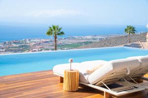 een ligstoel op een terras naast een zwembad bij Villa Kailani in Adeje