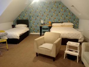 ein Dachgeschoss-Schlafzimmer mit zwei Betten und einem Stuhl in der Unterkunft Hill View Studio in Hawick