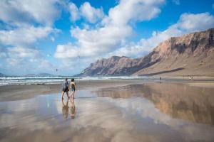 a man and woman walking on the beach at Famara Chill House in Famara