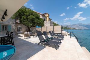 a group of chairs sitting on a patio next to the water at Seafront Kotor Bay View Villa NW in Muo