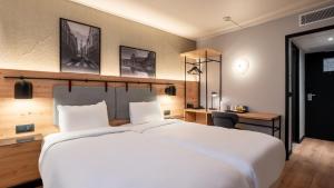 a bedroom with a large white bed and a desk at Campanile PRIME - Suresnes - La Défense in Suresnes
