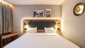 une chambre avec un grand lit blanc et une chaise dans l'établissement Campanile PRIME - Suresnes - La Défense, à Suresnes