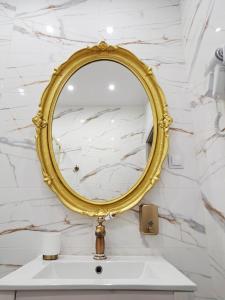 a bathroom with a gold mirror on a white marble wall at Poznaj Mickiewicza 2 in Racibórz +7 photos