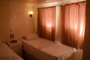 a small bedroom with two beds and a window at Floating Hotel- Happy Nile Boat in Luxor +5 photos