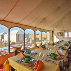 un gruppo di tavoli in una stanza con finestre di Diamante Luxury Camp a Merzouga