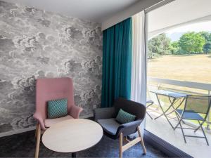 une chambre avec deux chaises, une table et une fenêtre dans l'établissement Mercure Aix-les-Bains Domaine de Marlioz Hôtel & Spa, à Aix-les-Bains
