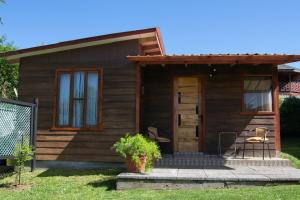a small wooden house with a porch and a chair at CABAÑAS RACO in Licán Ray