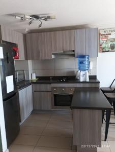 a kitchen with wooden cabinets and a black counter top at Departamento entero doble iquique in Iquique