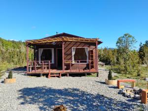 een kleine hut met een veranda op een grindterrein bij Cabaña colonia río sur in Puerto Varas