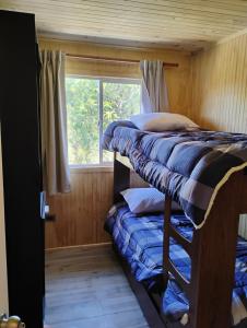 twee stapelbedden in een kamer met een raam bij Cabaña colonia río sur in Puerto Varas