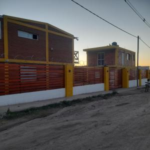 una recinzione di fronte a un edificio accanto a una strada sterrata di Zona Chalet a Los Molles