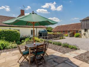 ein Tisch und Stühle mit einem grünen Sonnenschirm in der Unterkunft 2 Bed in West Knoyle 52105 in West Knoyle