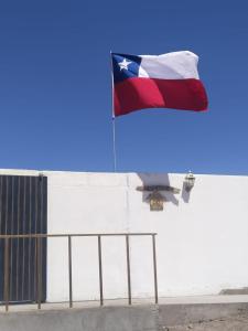 een vlag die wappert bovenop een witte muur bij Casa Dorada in San Pedro de Atacama