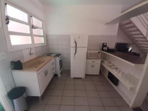 uma cozinha com uma geladeira branca e uma janela em Pousada Pantai Maresias em Maresias