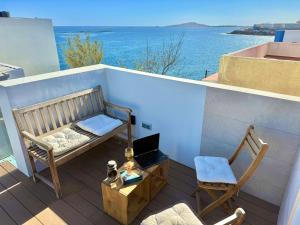 een balkon met een bank, een stoel en een laptop bij Melenara Beach in Melenara