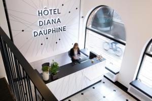 Una donna seduta alla scrivania di un hotel dharmaarmaphrinephrinephrinephrine. di Hôtel Diana Dauphine a Strasburgo