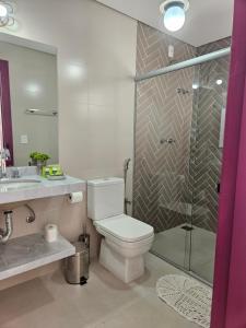 a bathroom with a toilet and a glass shower at Pousada Berço Mineiro in Tiradentes