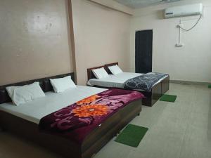 two beds sitting in a room with at Brajrani Hotel in Datia +7 photos